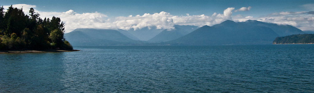 The Hood Canal and cloud capped Olympic Mountains on a sunny day panorama, part of the Puget Sound in western Washington state, USA